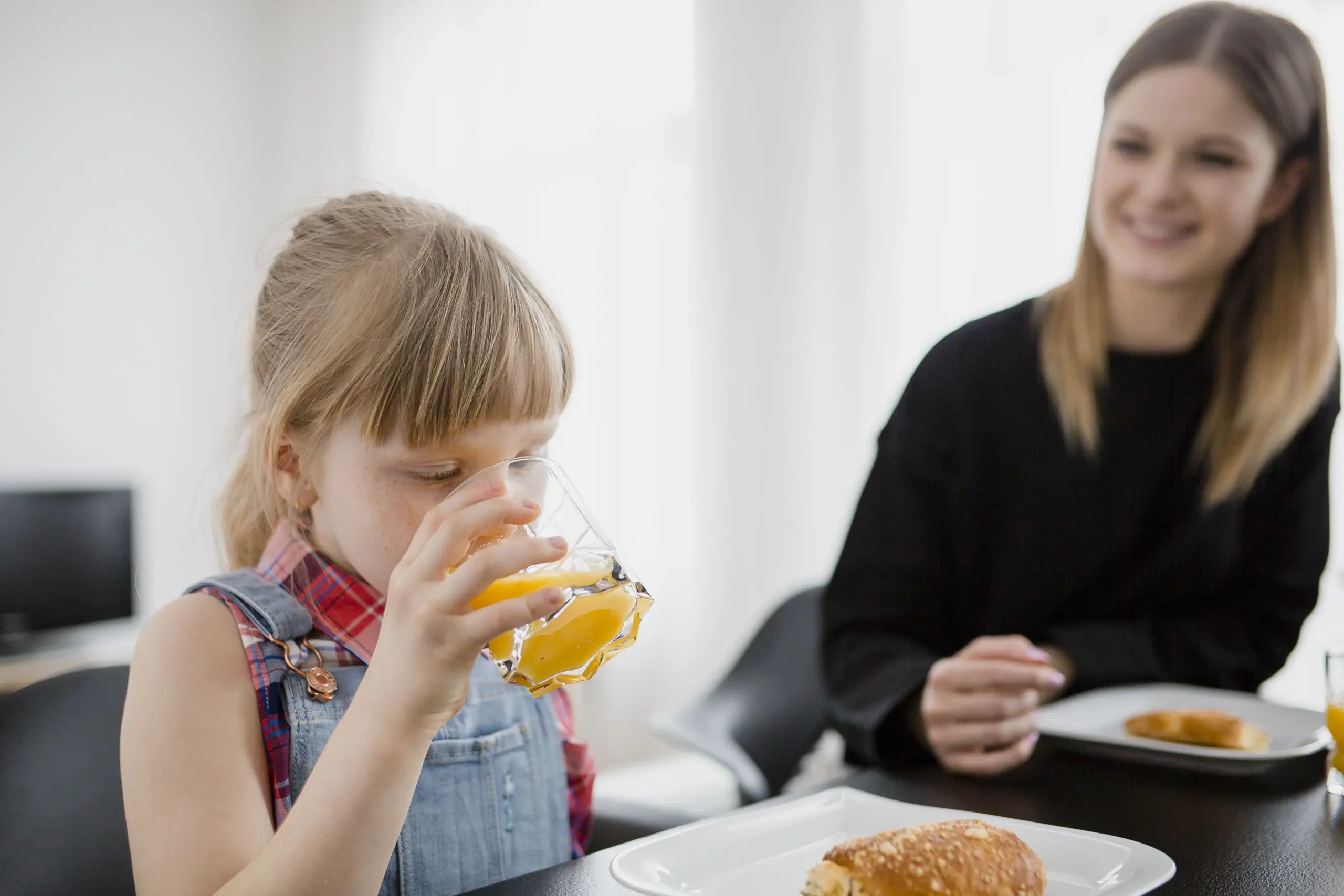 Criança com autismo bebendo um suco ao lado da mãe.